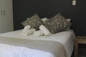 a bed with three pillows and towels on it at Guesthouse @ 31 Murray in Pretoria