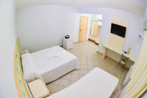 a large room with a bed and a television at Hotel Center in Xanxerê