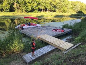 Ein Junge stand auf einem Dock mit einem Boot auf einem See. in der Unterkunft Serene Port Bay Cottage in Red Creek