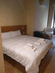 1 dormitorio con 1 cama blanca grande y toallas. en PALAZZO FULGHER, en Cagliari