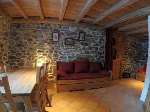 a living room with a red couch in a stone wall at VAUJANYLOCATIONS - Chalets Clovis I & II in Vaujany