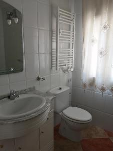 a white bathroom with a toilet and a sink at EL MIRADOR DEL CORNEJA in Mesegar de Corneja
