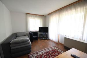 ein Wohnzimmer mit einem Sofa und einem TV in der Unterkunft Chalet Christina 7 in Arosa