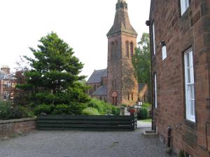 a church with a tall tower and a brick building at Dumfries Villa in Dumfries