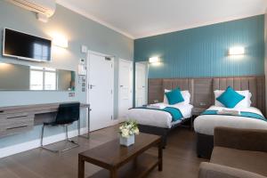 ein Hotelzimmer mit 2 Betten und einem TV in der Unterkunft SW1 Apartments in London