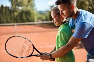 a man and a young boy holding a tennis racket at Kfar Maccabiah Business & Sport Hotel in Ramat Gan