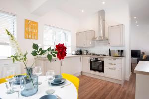 a kitchen with a table with a red flower in a vase at Flat B - Ground floor, 2 bedroom, 2 bathroom apartment with garden in Central Southsea, Portsmouth in Portsmouth