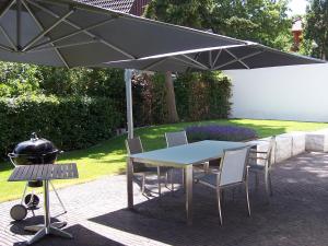 a table and chairs under an umbrella next to a grill at Refugium Prerow in Prerow