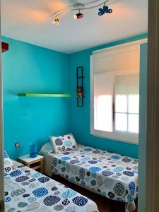 two beds in a room with blue walls at Apartamento Altafulla in Altafulla