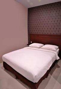 1 dormitorio con 1 cama grande y cabecero de madera en Grand Kebonsari Guesthouse, en Surabaya