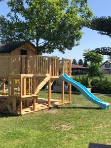 un parque infantil de madera con un tobogán en el césped en Szuflada Apartamenty, en Augustów