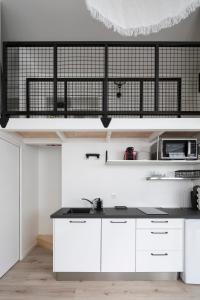 cocina con armarios blancos y encimera negra en L'Instant by Cocoonr, en Rennes