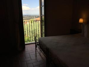 um quarto com uma cama e vista para uma varanda em Agriturismo Borgo tra gli Olivi em Castiglion Fiorentino