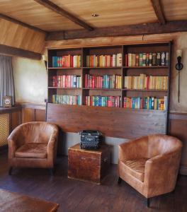 ein Zimmer mit 2 Stühlen und einem Bücherregal mit Büchern in der Unterkunft Hotel Abdij de Westerburcht in Westerbork