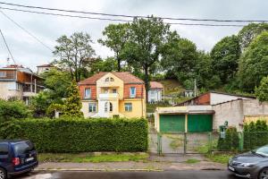 a yellow house with a fence in a city at Bright and Cosy 1BDR apartment Kaunas Centre in Kaunas