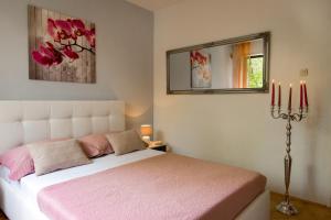 a bedroom with a bed with pink sheets and a mirror at Villa Palma Karojba in Karojba