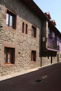 a stone building with windows on a street at Posada El Arrabal in Arenas de Iguña