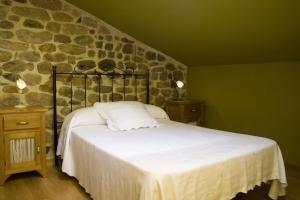 1 dormitorio con cama y pared de piedra en Posada El Arrabal, en Arenas de Iguña