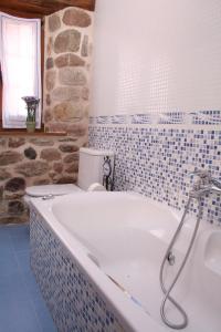 uma banheira na casa de banho com uma parede de pedra em Posada El Arrabal em Arenas de Iguña
