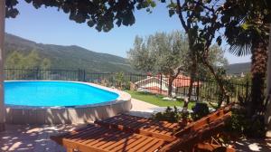 a pool in a yard with benches and a house at VILLA ČEH in Gabrovica pri Črnem Kalu