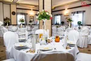 a room with white tables with white chairs and flowers at Hotel Zodiak in Radomsko