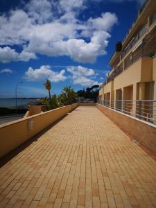 uma passarela de tijolos que leva a um edifício com um céu nublado em T1 Sea & Pool em Caxias