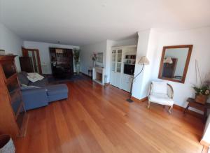 uma sala de estar com um sofá azul e piso em madeira em T1 Sea & Pool em Caxias