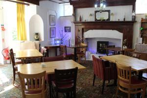 a restaurant with wooden tables and chairs and a fireplace at The Darnley Hotel in Ilfracombe