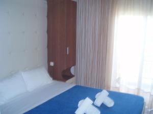 a bedroom with a bed with two white towels on it at Kopsis Beach Hotel in Pefkochori