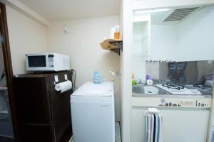 uma pequena cozinha com um micro-ondas e um frigorífico em Cozy house 8, free wifi a rented electric bicycle em Quioto
