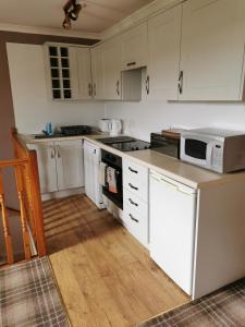 uma cozinha com armários brancos e um micro-ondas branco em Greannan Upper Self Catering Apartment em Blackwaterfoot