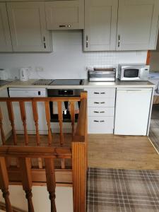 a kitchen with white cabinets and a wooden bench at Greannan Upper Self Catering Apartment in Blackwaterfoot