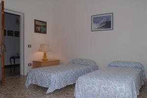 a bedroom with two beds and a lamp on a table at Casa Vacanza La Palma in Massa