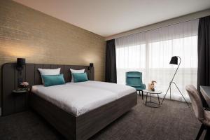 a bedroom with a large bed and a blue chair at Van der Valk Hotel Brussels Airport in Diegem