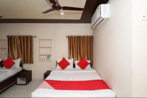 a bedroom with two beds with red pillows at Hotel R D Palace in Varanasi