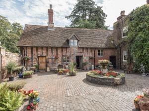 un vieux bâtiment en briques avec des fleurs dans une cour dans l'établissement Courtyard Cottage, à Great Bolas