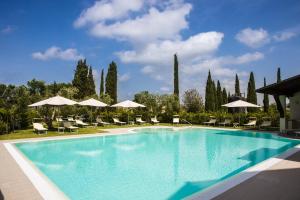 a large swimming pool with chairs and umbrellas at Borgo Venecca in Fonteblanda