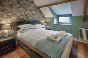 a bedroom with a large bed and a stone wall at The Hay Barn - Llyn Peninsula in Nefyn