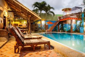 a pool with two lounge chairs next to a building at Lala Panzi Bed and Breakfast in Puerto Princesa City