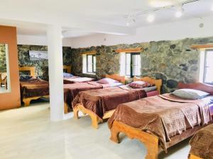 una camera con quattro letti e un muro di pietra di Manoni Ratiani's Guesthouse a Mestia