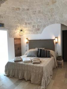 Trulli Pietraverde في سيغلي ميسابيكا: غرفة نوم بسرير كبير بسقف حجري
