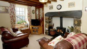a living room with leather furniture and a stone fireplace at Dinas Cottage in Penrhyndeudreath