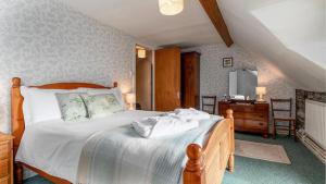 1 dormitorio con cama con sábanas blancas y escritorio en Maes Glas, en Mallwyd