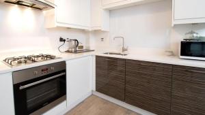 a kitchen with white cabinets and a stove top oven at Eleven in Deganwy