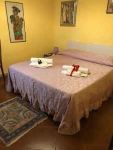 a pink bed with towels and a red ribbon on it at Appartamento del cuore in Pitigliano