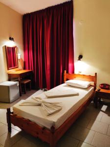 1 dormitorio con 1 cama con cortina roja en Titania Hotel Karpathos, en Karpathos