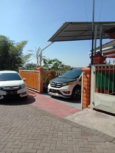 dos autos están estacionados en un estacionamiento en Homestay Andari, en Batu