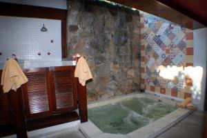 a bathroom with a tub with a stone wall at Hotel El Cazar in Búzios