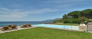 - une piscine avec des chaises longues et l'océan dans l'établissement La Florentine, à Saint-Florent