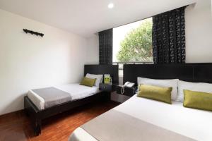 1 dormitorio con 2 camas y ventana en Hotel Dorado 100, en Bogotá